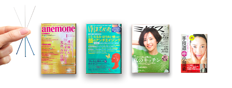 手技道協会のウェブサイトの画像。左側に、手で持たれた鍼のセットが表示されており、右には健康や美容に関連する日本の雑誌や書籍の表紙が4冊並んでいる。