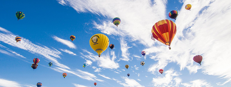 青空に浮かぶ色とりどりの熱気球の群れが、健康促進と癒しの技術を象徴しています。